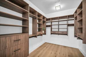 Walk in closet with light wood finished floors
