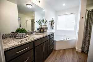 Full bath featuring vanity, dark wood-type flooring, a garden tub, a shower with shower curtain, and recessed lighting
