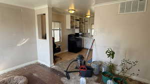 Kitchen with black electric range, ornamental molding, white cabinets, and stainless steel microwave