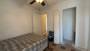 Bedroom with ornamental molding, tile patterned floors, and ceiling fan