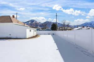 Yard covered in snow featuring a fenced backyard and a mountain view