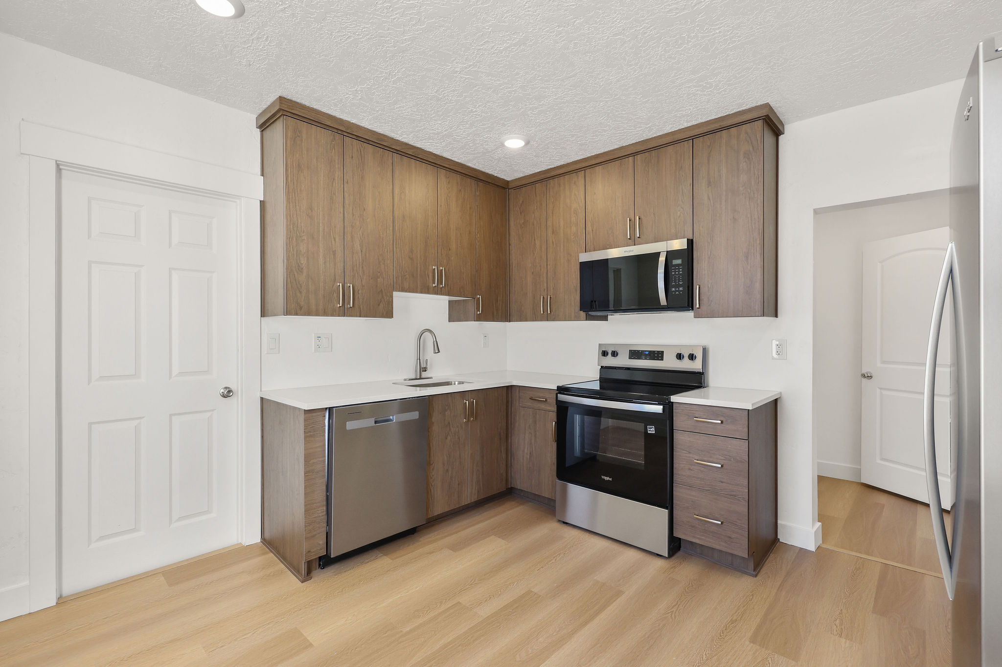 Kitchen featuring stainless steel appliances, modern cabinets, light wood-style flooring, recessed lighting, and light stone countertops