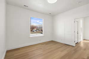Spare room featuring light wood-type flooring and a textured ceiling