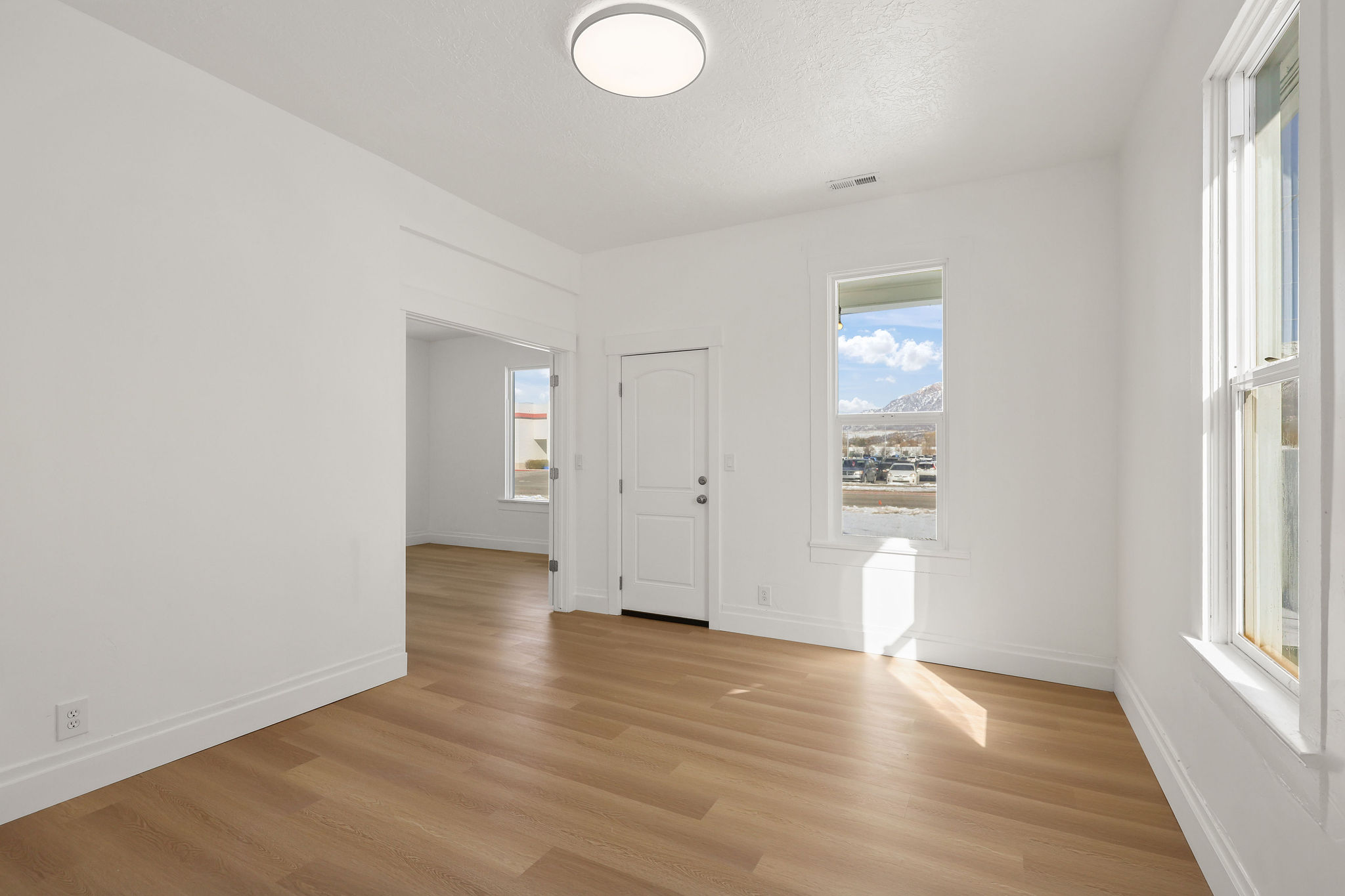 Unfurnished room with light wood-type flooring, healthy amount of natural light, and a textured ceiling