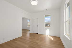 Unfurnished room with light wood-type flooring, healthy amount of natural light, and a textured ceiling
