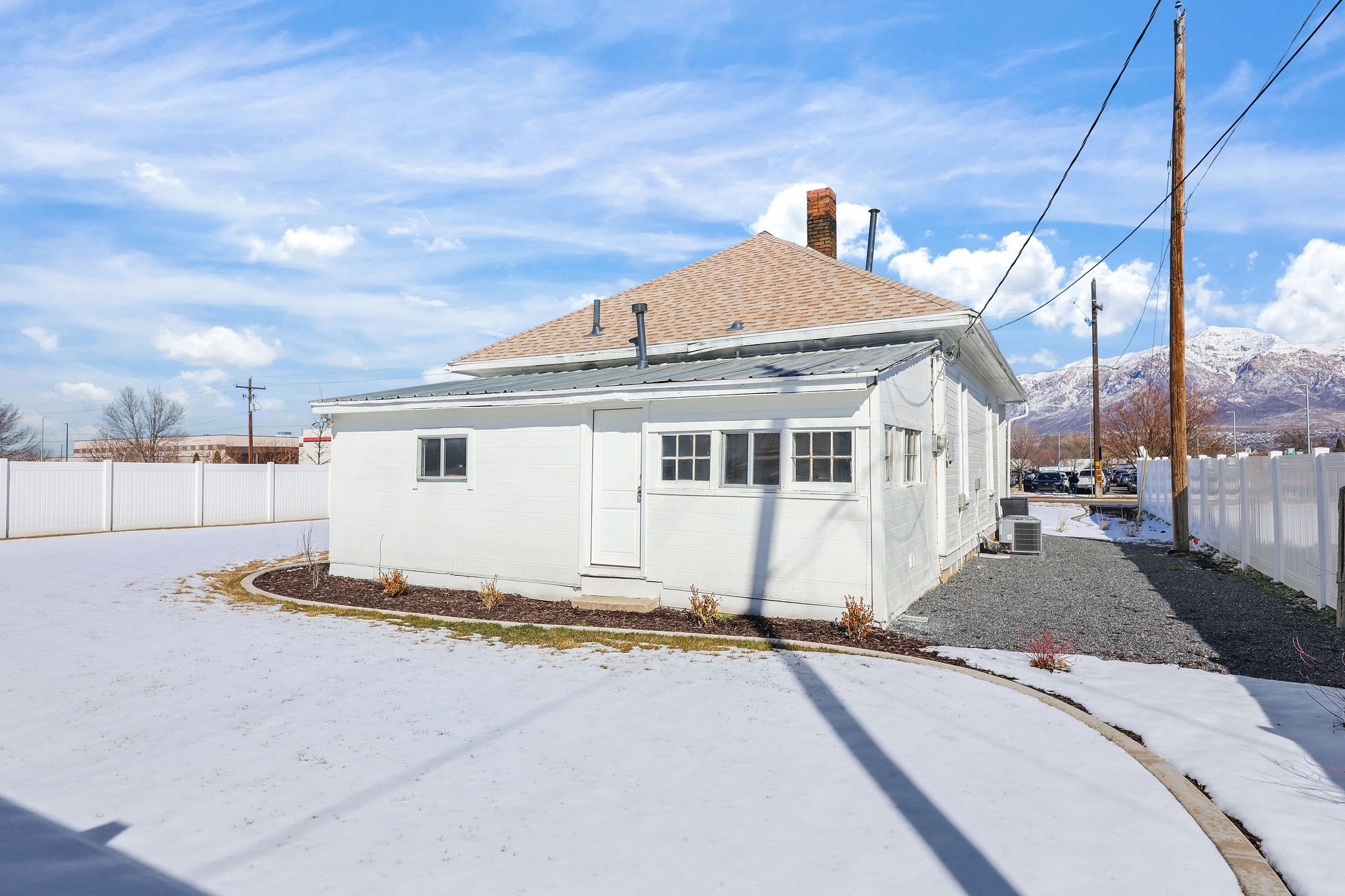 Rear view of house with a fenced backyard, roof with shingles, a chimney, and a mountain view