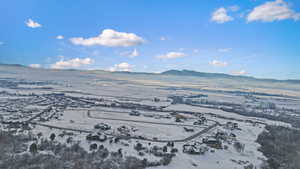 Snowy aerial view featuring a mountain view and a view of countryside