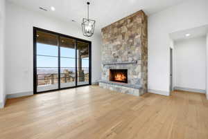 Unfurnished living room with light wood finished floors, a fireplace, and hanging lights
