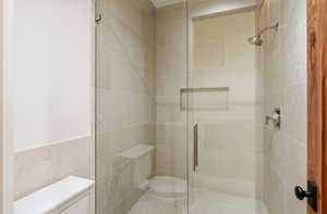 Full bath with a shower stall and tile walls