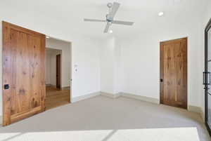 Unfurnished bedroom with light carpet, ceiling fan, and recessed lighting