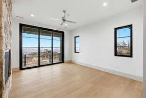 Unfurnished room with ceiling fan, light wood-style flooring, recessed lighting, and a fireplace