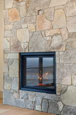 Detailed view of wood finished floors and a stone fireplace