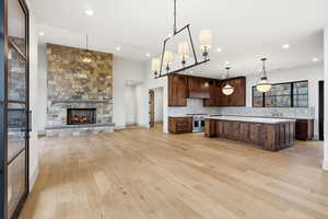 Kitchen with open floor plan, light countertops, an island with sink, dark wood finish cabinetry, and a fireplace