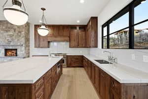 Kitchen featuring a stone fireplace, light wood-style floors, light stone counters, and tasteful backsplash