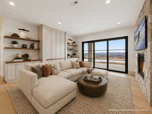 Living room with light wood-style floors, a fireplace, and recessed lighting