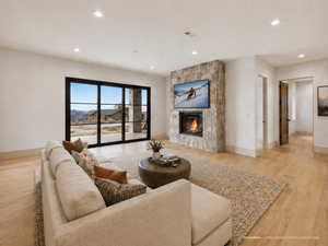 Living room featuring light wood finished floors, a fireplace, and recessed lighting