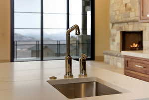 Kitchen view of light countertops, a stone fireplace, and wood finish cabinetry