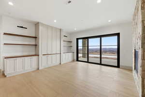 Unfurnished living room featuring light wood finished floors, a stone fireplace, and recessed lighting