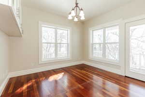 Unfurnished dining area featuring a chandelier and dark wood-style flooring