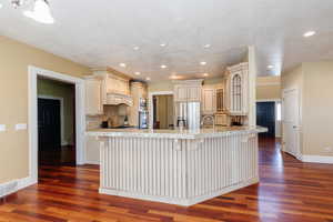Kitchen featuring dark wood-style flooring, a breakfast bar area, cream cabinets, stainless steel appliances, and recessed lighting