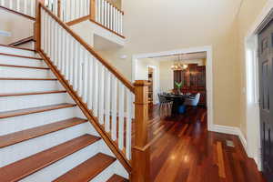Staircase with wood-type flooring, a chandelier, and a high ceiling