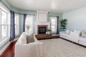 Living area with wood finished floors, a brick fireplace, and recessed lighting