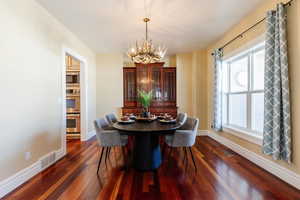 Dining area featuring dark wood-style flooring and a chandelier