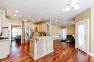 Kitchen featuring a kitchen bar, stainless steel fridge with ice dispenser, a chandelier, light wood finished floors, and a textured ceiling