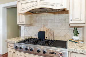 Kitchen featuring stainless steel gas cooktop, cream cabinets, and light stone counters
