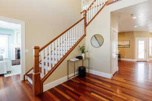 Stairs featuring wood-type flooring, recessed lighting, and a brick fireplace