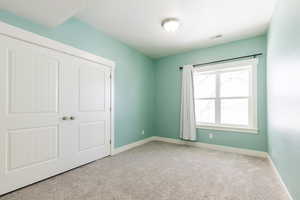 Unfurnished bedroom with light carpet and a closet