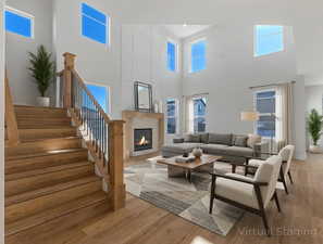 Living area featuring a high ceiling, light wood-type flooring, healthy amount of natural light, and a glass covered fireplace
