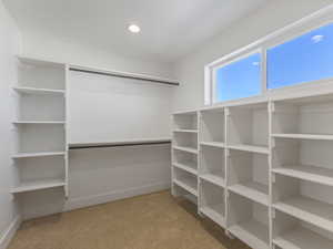 Walk in closet with light colored carpet