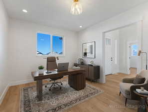 Home office with light wood finished floors, plenty of natural light, and recessed lighting