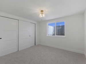 Unfurnished bedroom featuring light carpet and a closet