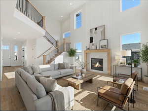 Living room with wood finished floors, a high ceiling, a glass covered fireplace, and recessed lighting