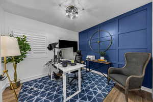 Office featuring a decorative wall, dark wood-style flooring, and an accent wall