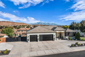 View of front of house featuring an attached garage, a mountain view, stone siding, and concrete driveway