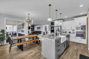Kitchen featuring dual tone cabinets, a kitchen breakfast bar, open floor plan, light wood-style floors, and stainless steel appliances