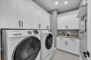 Laundry area featuring washing machine and clothes dryer, cabinet space, and recessed lighting