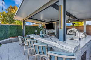 Fenced backyard featuring ceiling fan, a patio, and an outdoor kitchen
