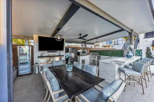 View of patio with an outdoor kitchen, an outdoor bar and dining area, and a ceiling fan