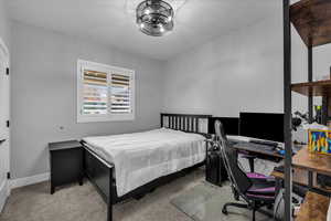 Bedroom featuring light carpet and a desk