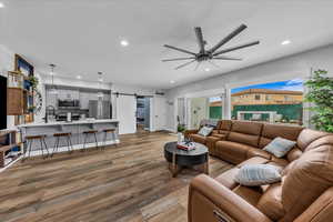 Living room featuring a barn door, light wood finished floors, recessed lighting, and ceiling fan
