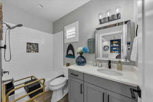 Bathroom with vanity, shower / bath combination, and dark wood finished floors
