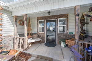 Doorway to property with covered porch and stone siding
