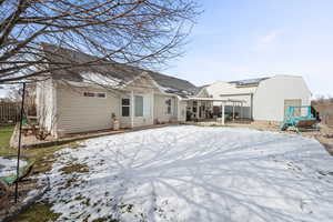 Snow covered rear of property featuring a patio area and a pergola