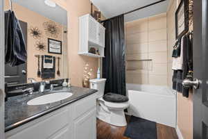 Full bathroom featuring vanity, shower / bath combo, and dark wood-type flooring