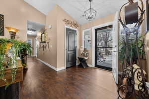 Foyer entrance featuring dark wood-style flooring, lofted ceiling, and suspended lighting