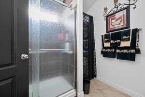 Bathroom with a shower stall and wood finished floors
